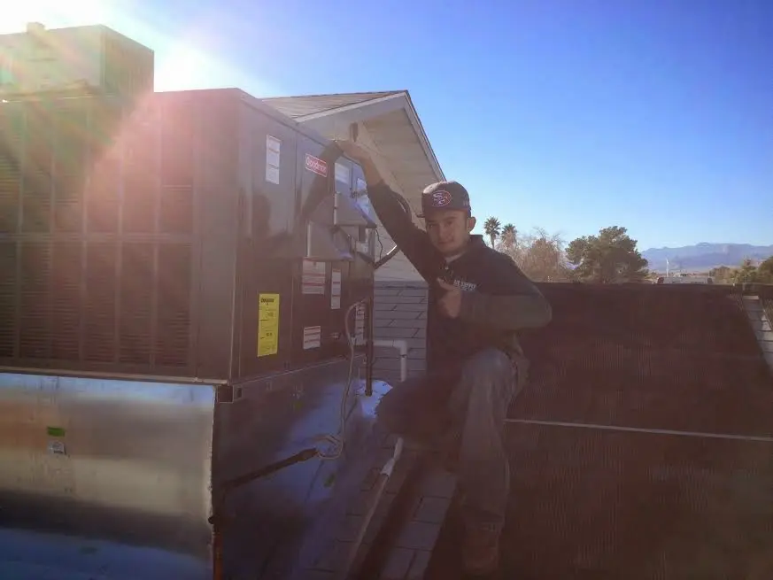 HVAC technician performing HVAC Inspection on a rooftop unit in Homer